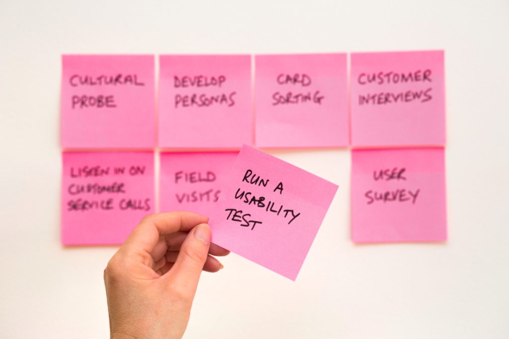 Pink post it notes on a wall with tasks to do because market research is important. 